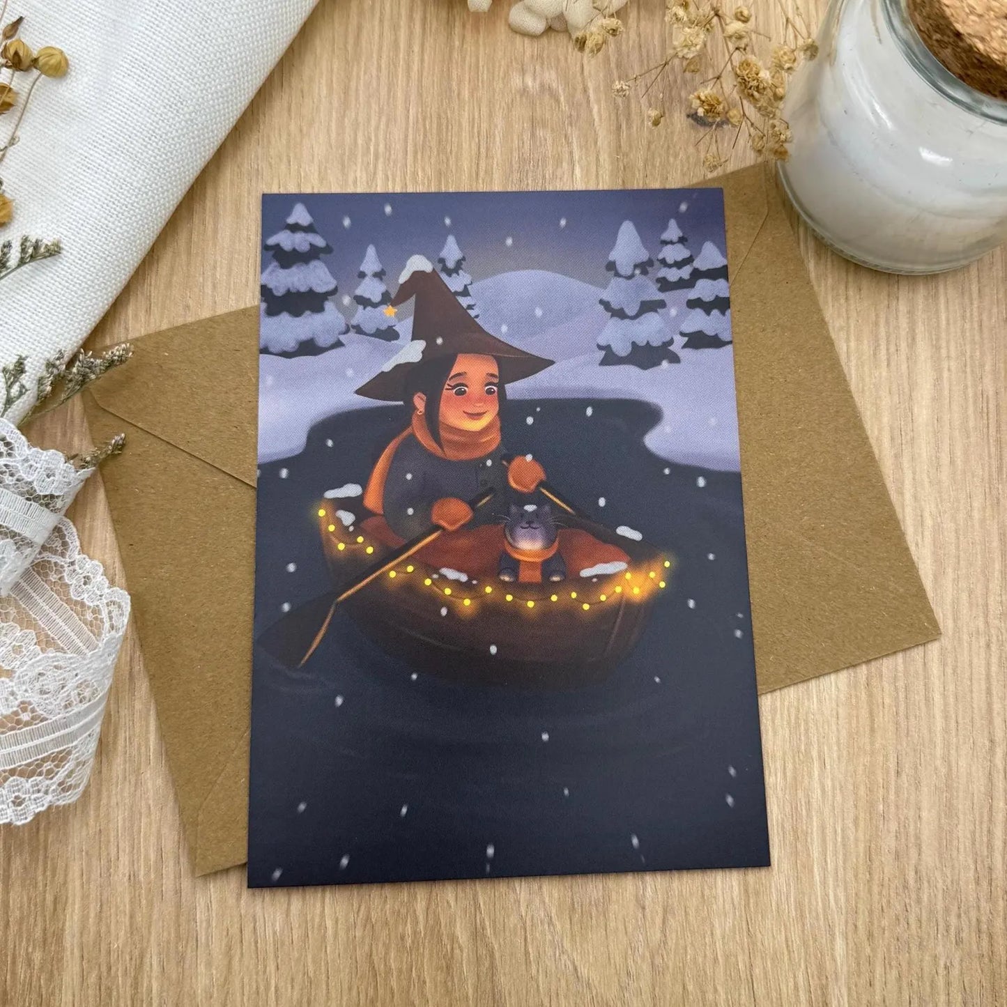 Postkarte „Winter Witch Boat“ – Winterliche Hexe auf dem See | Magische Winterkarte mit Katze & Lichterkette
